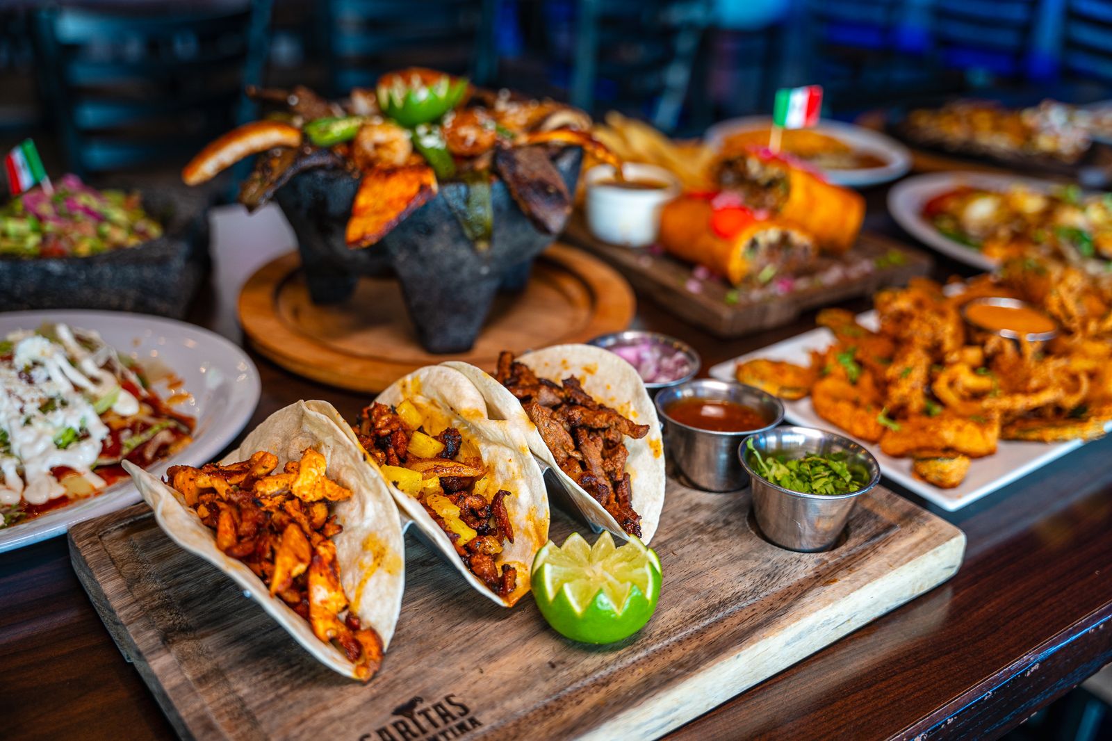 Street tacos, molcajete and appetizers on a wooden board